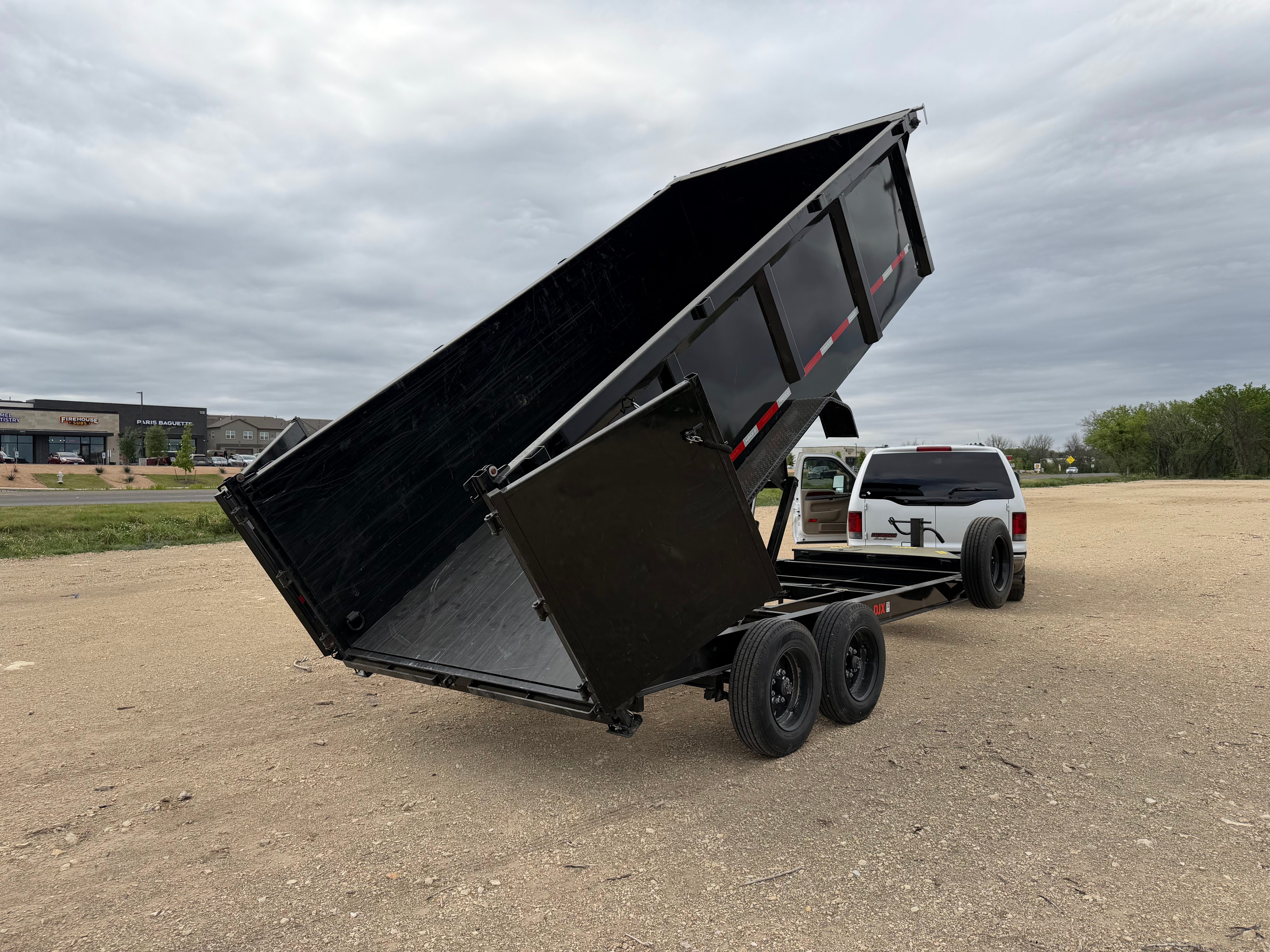 Maxx-D DJX dump trailer bed raised with white SUV hitched