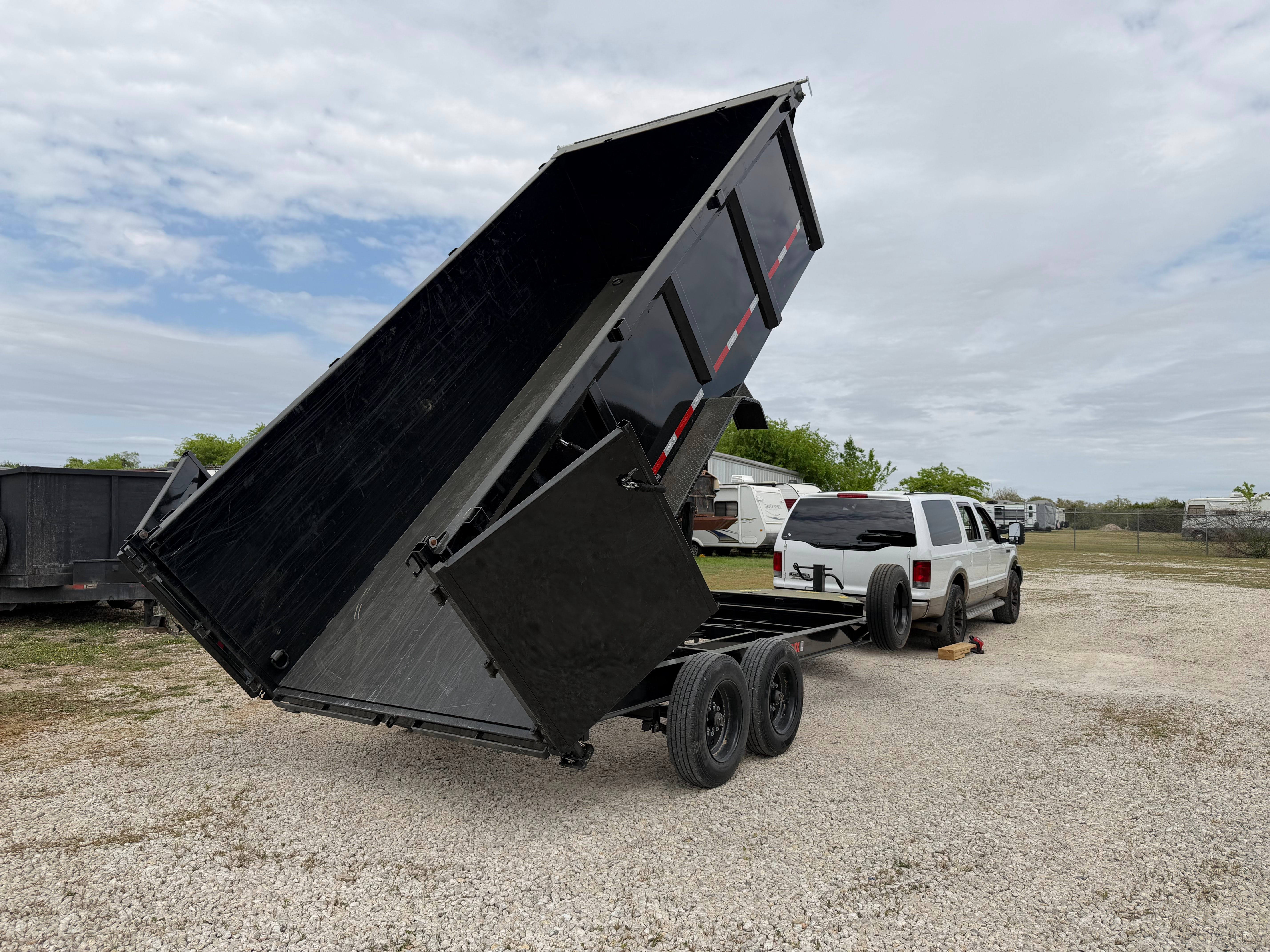 Maxx-D DJX dump trailer bed raised high with white truck